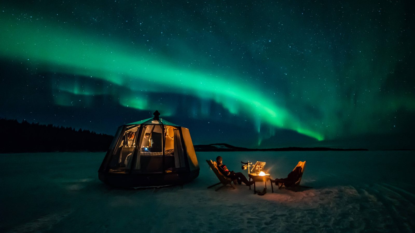 An aurora over a glass hut on frozen Lake Inari, Finnish Lapland