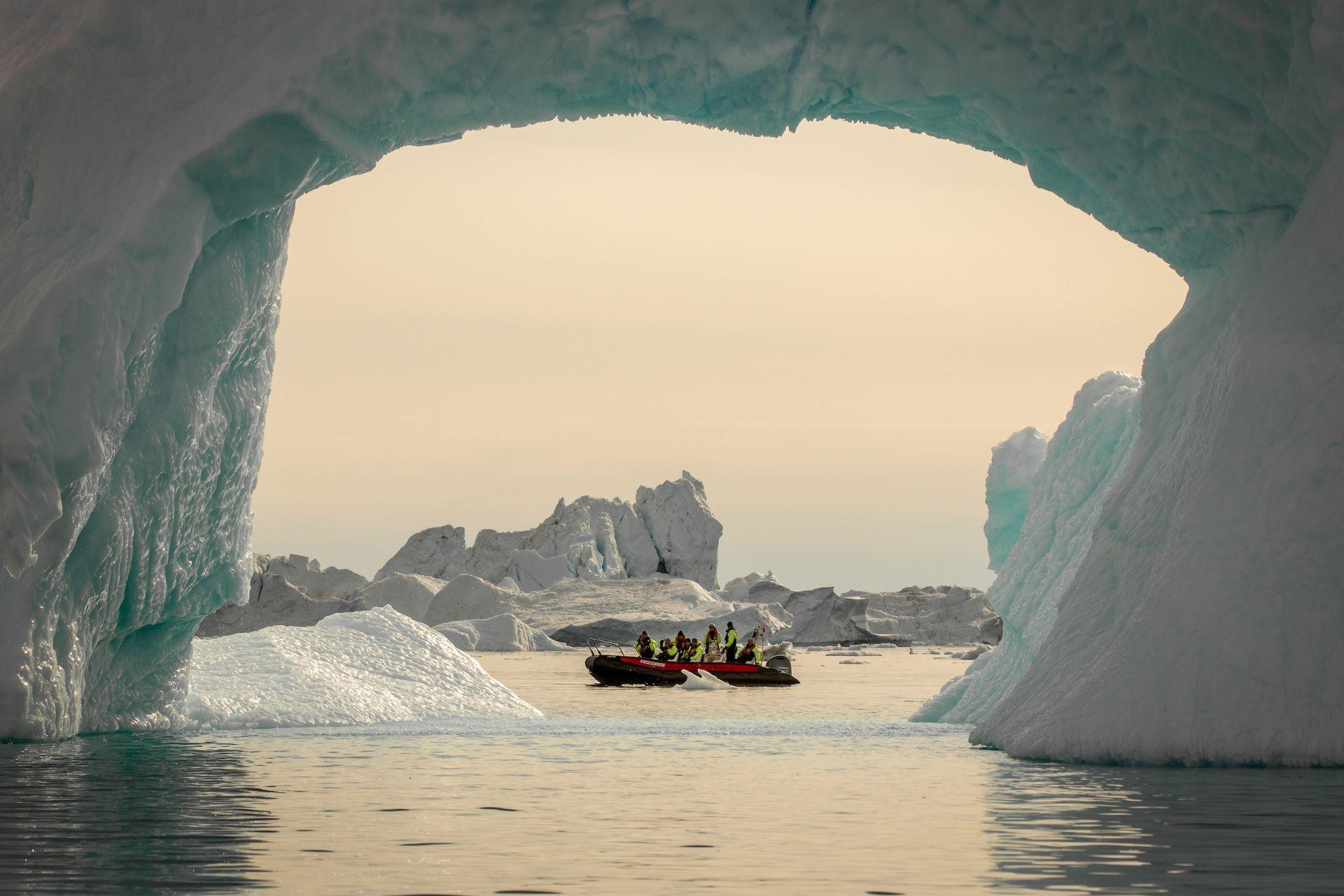 A boat seen through an iceberg arc in the Disko Bay