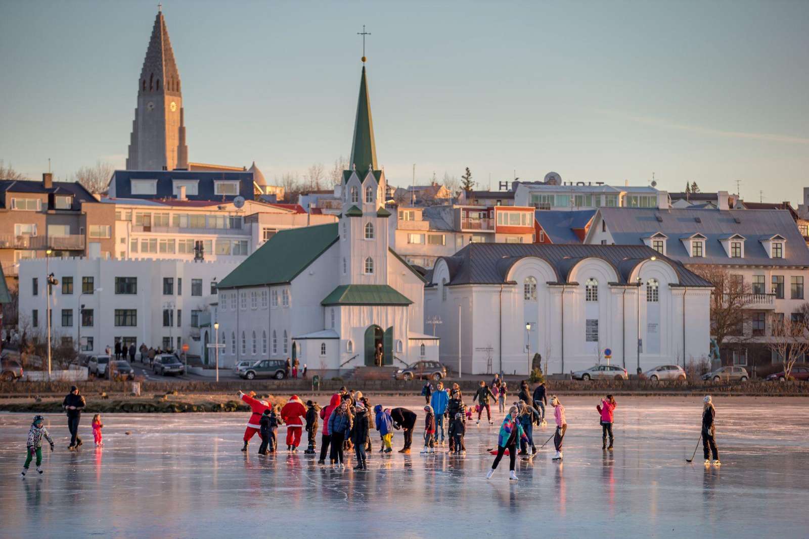 Ice skaters on Tjörnin pond with Fríkirkjan church, Reykjavík